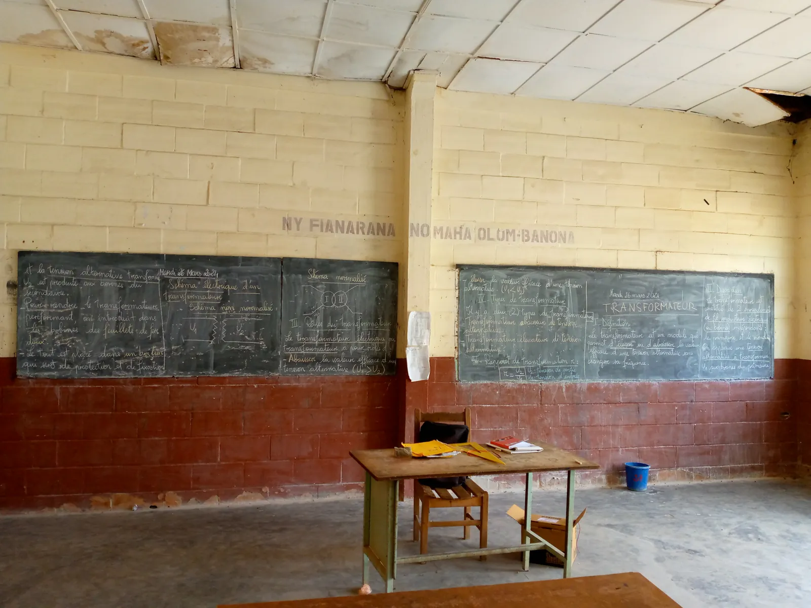 Deux tableaux couverts du cours complet sur le transformateur, sous la devise « Ny fianarana no maha olom-banona » peinte au mur