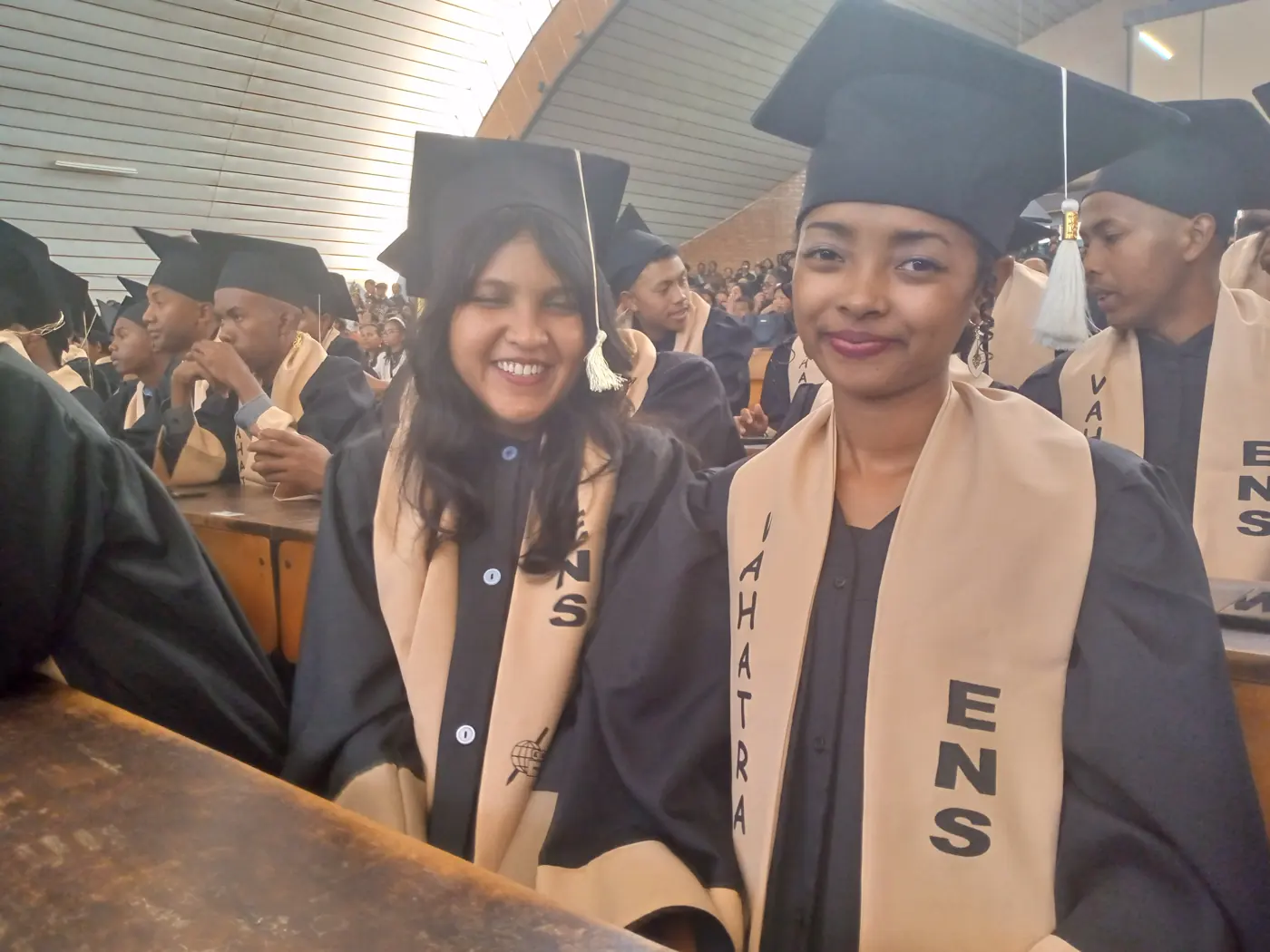 Niriantsoa, souriante en toge et écharpe ENS, dans l'amphithéâtre lors de la cérémonie de remise des diplômes