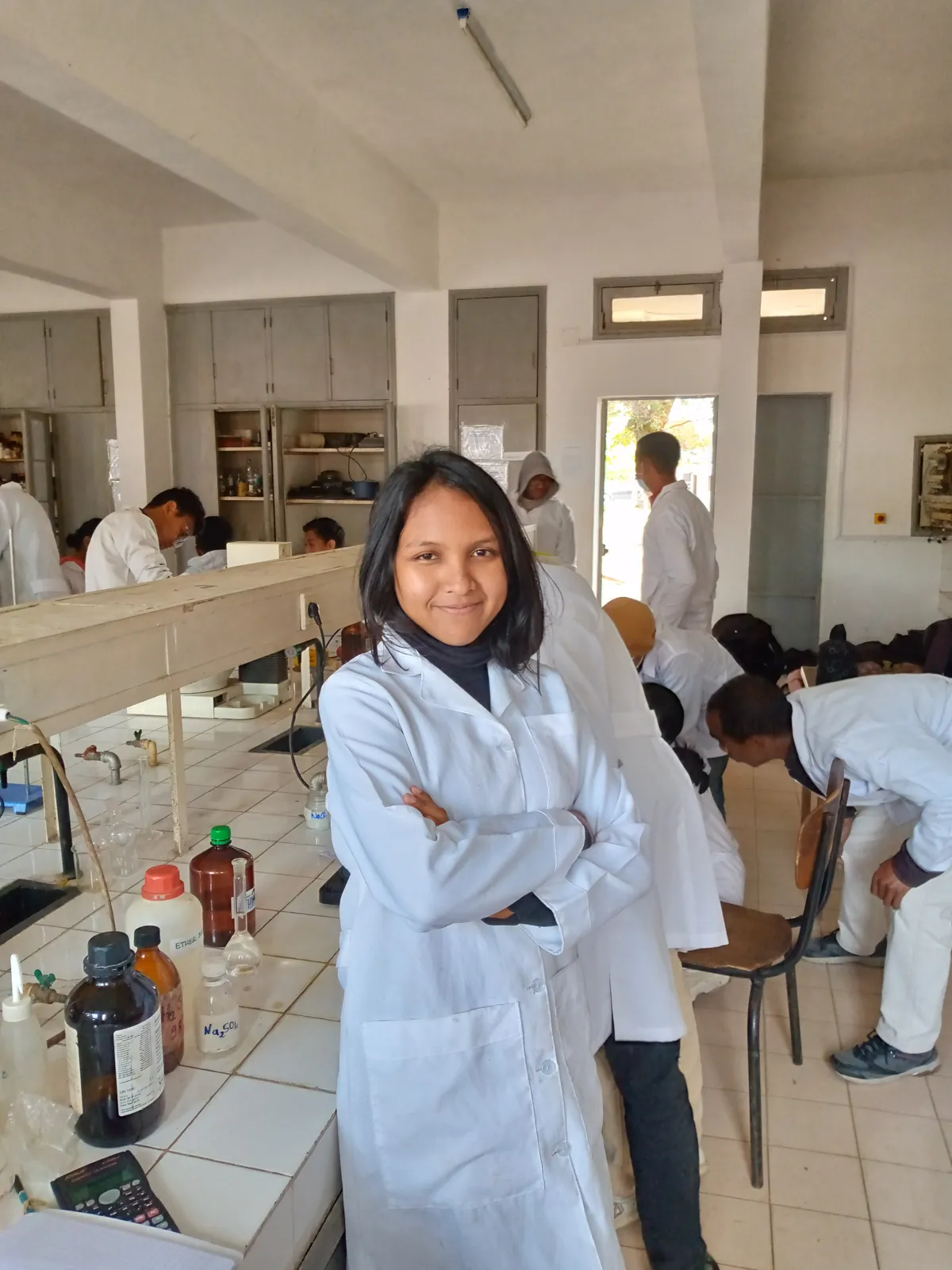 Niriantsoa souriante en blouse blanche, bras croisés, dans un laboratoire de chimie