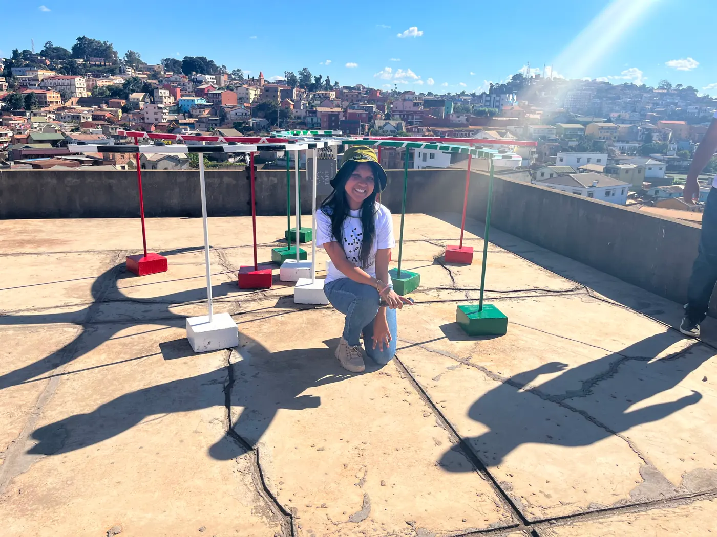 Niriantsoa accroupie devant les antennes du TART, peintes aux couleurs du drapeau malgache, sur un toit d'Antananarivo
