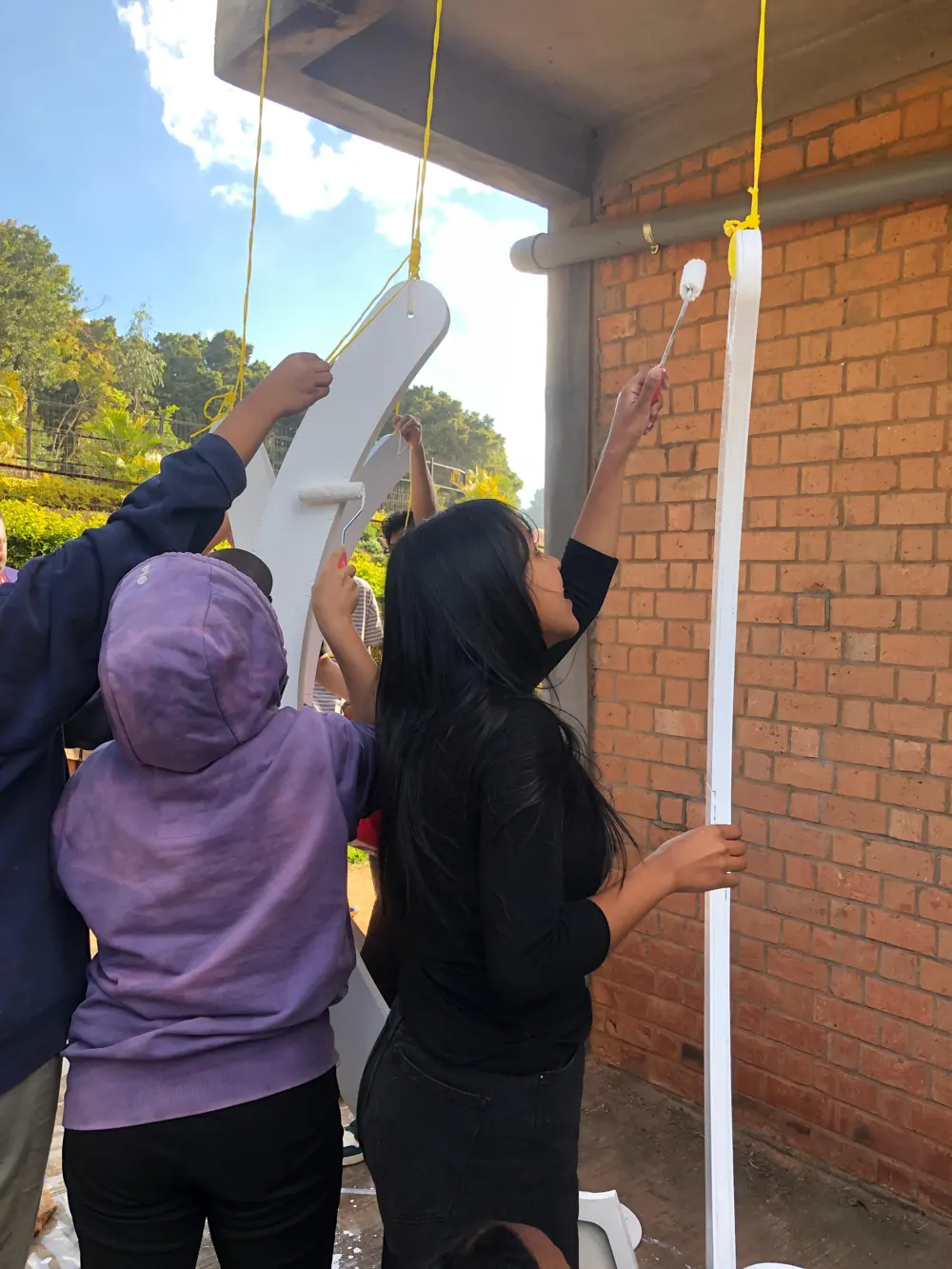 Niriantsoa et d'autres participants peignent en blanc les supports d'antennes du télescope TART